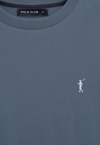 Maglietta blu di media misura con scollo tondo e logo Polo Club bianco ricamato sul petto, raffigurante un golfista con una mazza da golf.