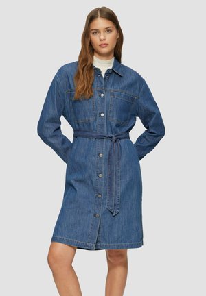 Robe en denim avec un devant à boutons, deux poches poitrine et une ceinture nouée. Confectionnée en denim bleu de poids moyen, avec des manches longues et un ourlet légèrement évasé.