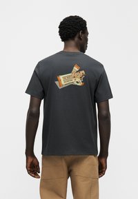 Σκούρο γκρι βαμβακερό T-shirt με στρογγυλή λαιμόκοψη, με γραφικό απομίμησης μπάρων σνακ στην πλάτη, που αναδεικνύει χρώματα πορτοκαλί, κρεμ και καφέ.