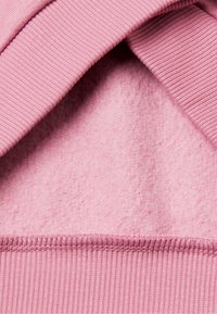 Tessuto in pile rosa con texture a coste sui bordi. Il materiale è morbido e liscio, con una tonalità uniforme in tutto.