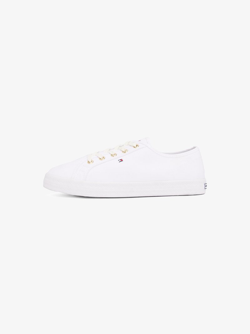 Sneakers en toile blanches avec œillets dorés, lacets plats, semelle en caoutchouc texturée et branding minimal sur le côté. Design bas.