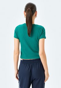 Grønneribbet crop top med korte ærmer, parret med navy joggere med elastisk talje. Toppen har en glat tekstur og en tætsiddende pasform.