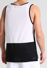 Canotta sportiva da uomo con parte superiore in rete bianca e parte inferiore nera con un design testurizzato e marchio DRI-FIT sull'orlo.