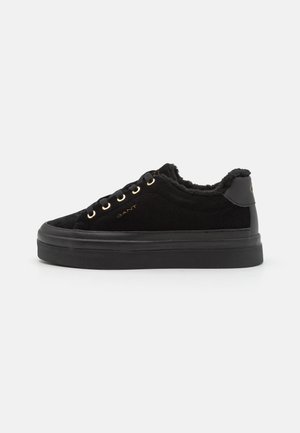 Schwarze Wildleder-Sneaker mit einem flauschigen Innenfutter, goldenen Ösen und einer dicken schwarzen Gummisohle. Enthält minimale Branding auf der Seite.