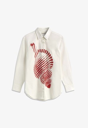 Chemise blanche à manches longues avec col et boutons, présentant un grand motif abstrait rouge en spirale sur le côté avant gauche.