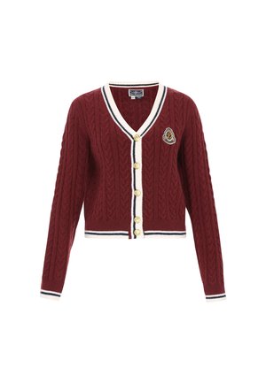 Burgundi színű, kötött cardigan V nyakkal, gombos záródással, krém színű díszítéssel, valamint tengerészkék és fehér csíkozással. Egy díszítő folt is található rajta.