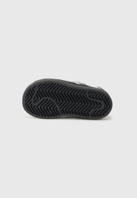 Semelle en caoutchouc noir de sneakers avec un motif de semelle en zigzag, bords lisses et une forme de bout arrondi.