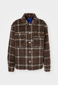 Brązowa, kremowa i czarna pikowana wełniana kurtka z kołnierzykiem koszulowym, zapięciem na guziki oraz dwiema kieszeniami na piersi z klapami.