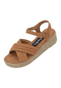 Tan suede wedge sandal with crossed straps, textured upper, ankle buckle, and a woven jute sole. Flat heel design for stability.