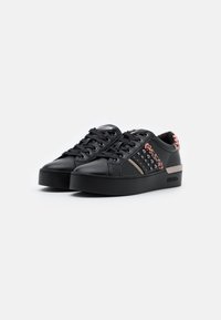 Schwarze Sneakers mit einem glatten Lederoberteil, einer Plattformsohle, Nietenakzenten und einem gemusterten rosa und schwarzen Absatz.