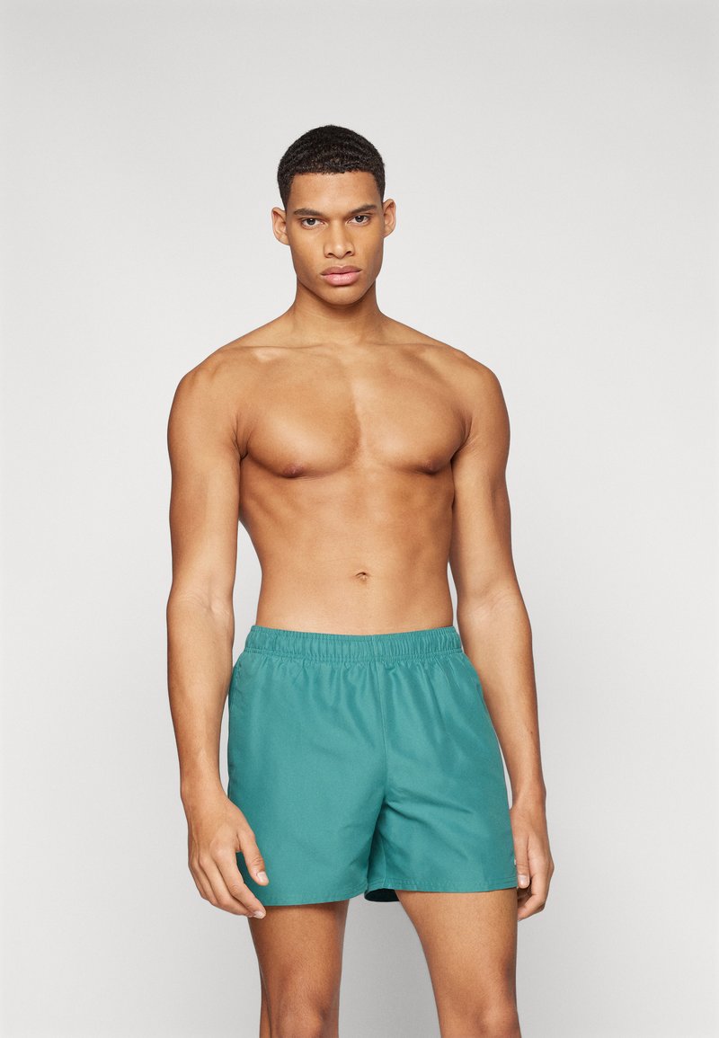 Shorts de bain teal avec une taille élastique, fabriqués en matériau léger, présentant un design simple et une coupe décontractée.