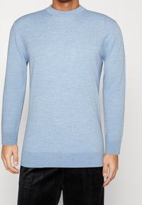Pull bleu clair à col rond fait en matériau en tricot doux. Manches longues avec des poignets et un ourlet côtelés. Texture lisse, design simple, motifs minimaux.
