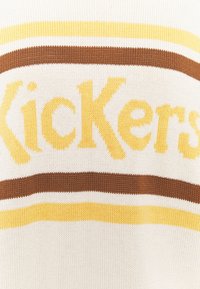 Sweter z dzianiny o kremowej bazie, z żółtymi i brązowymi paskami, z wyraźnie wyświetloną wytłoczoną żółtą czcionką nazwą "Kickers".