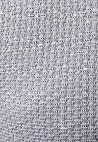 Grijze geweven stof met een gemêleerd patroon van kleine, herhalende ovalen en hexagons, die een zichtbare tactiele oppervlakte biedt.