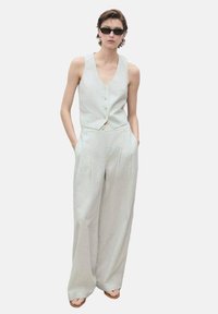Lys grå, ærmeløs vest med knapper, parret med brede bukser. Glat tekstur, minimalistisk design og løs pasform for komfort.