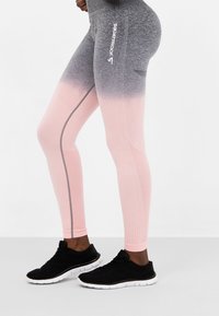 Rosa och grå graderade leggings med texturerade sektioner, squat-säkert utformade och reflekterande detaljer; kombinerade med svarta träningsskor.