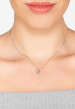 Silver necklace with a teardrop-shaped blue gemstone pendant, featuring a delicate chain and a polished surface, set against a neutral background.