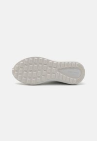 Witte rubberen sneakersole met een gestructureerd grippatroon, ovale teenvorm en subtiele branding aan de zijkant. Gemiddeld verhoogde hak.