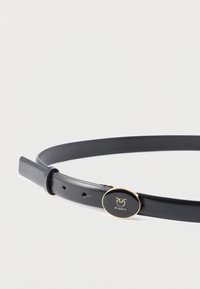 Ceinture en cuir noir à texture lisse, dotée d'une boucle ronde de couleur dorée avec un détail de logo. Ajustable grâce à des trous le long de la sangle.
