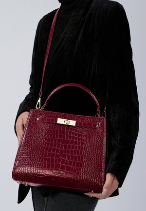 Sac à main en cuir gaufré crocodile cramoisi avec un design structuré, ferrures dorées, bandoulière détachable et poignée supérieure.