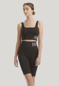 Svart ribbad croptop och högmidjade shorts-set, med en fyrkantig halsringning och logotryck i grått. Slät textur och figurnära design.