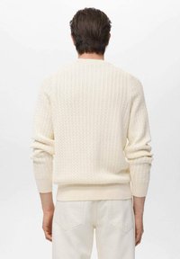 Suéter crema de canalé con superficie texturizada y mangas largas, que presenta un cuello redondo y una cinturilla ajustada.