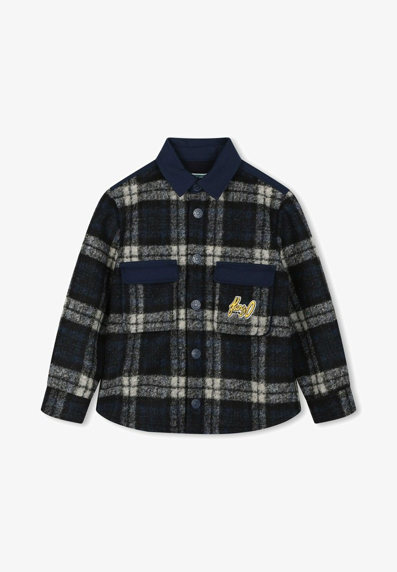Veste en laine à carreaux noirs et gris avec col bleu marine, fermeture par boutons, deux poches poitrine et logo brodé jaune sur la poche gauche.