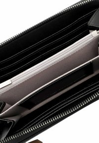 Portafoglio nero con esterno in pelle liscia, chiusura con zip, numerosi slot per carte e un compartimento foderato in tessuto beige con tasca con zip.