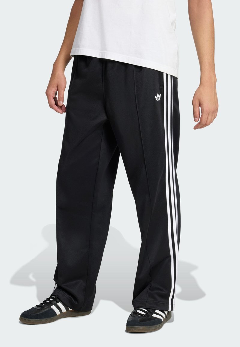 Crne sportske hlače s bijelim trostrukim prugama uz bokove, izrađene od glatke, lagane tkanine, s izvezenim logotipom na bedrima.