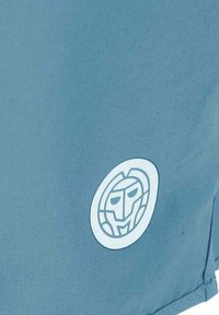 Pantalones cortos de tela azul con un logo blanco redondo que presenta una cara similar a la de un león. El material parece ligero y con una textura suave.