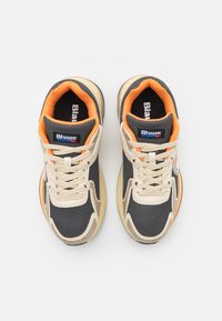 Sneaker grigie e beige realizzate con materiali in rete e pelle, con accenti arancioni, punta arrotondata e lacci a contrasto. Logo sulle linguette.