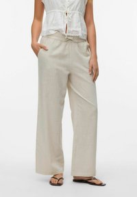Lichtbeige, wijde broek gemaakt van een geweven stof, met een elastische tailleband en zijzakken, gecombineerd met een witte top.