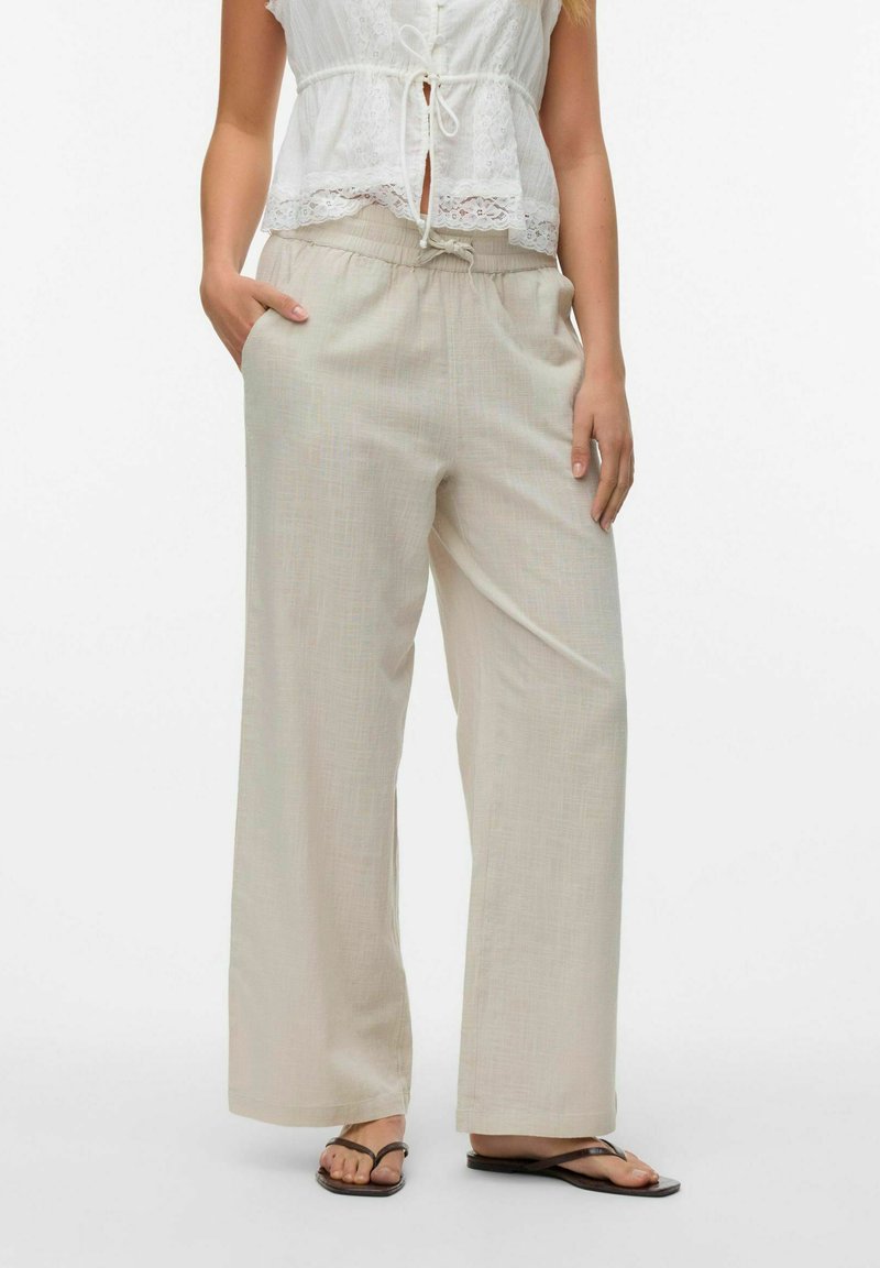 Lichtbeige, wijde broek gemaakt van een geweven stof, met een elastische tailleband en zijzakken, gecombineerd met een witte top.