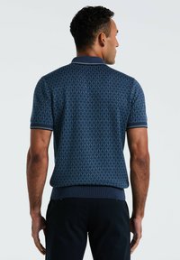 Polo bleu marine avec un motif géométrique, à manches courtes, et col et poignets côtelés. Présente une coupe slim et un tissu texturé.