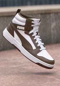 High-top sneakers with a brown and white leather exterior, perforated toe box, padded collar, and prominent "PUMA" logo on the side.