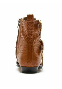 Stivaletto alla caviglia in pelle marrone con finitura testurizzata, dotato di cerniera laterale e doppi dettagli con fibbia in tonalità oro sul lato esterno.