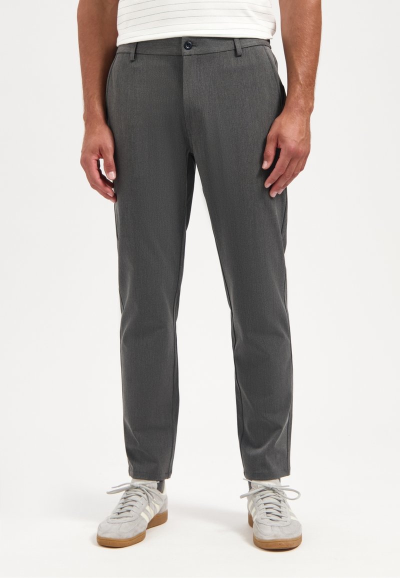 Grijze op maat gemaakte broek van gladde stof, met een slim fit, flatte voorkant en standaard zakken, gecombineerd met lichtgekleurde sneakers.