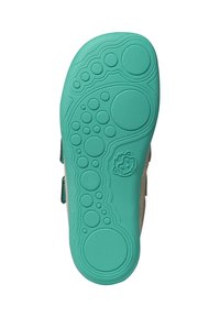 Turquoise sole of a sandal featuring circular textured patterns and a small embossed smiling face near the arch area.