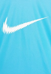 Camiseta deportiva de color azul claro con un gran logo de swoosh blanco de Nike en un diseño dinámico. Textura de tela suave, con mangas cortas.