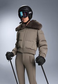 Khaki színű, bélelt dzseki műszőrmés gallérral, barna sínadrág, fekete kesztyű és sisak. Kék színű szemüveg és letisztult dizájn jellemzi.