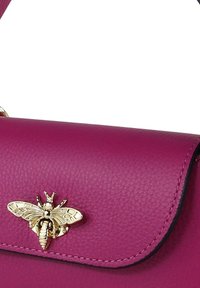 Magenta leren handtas met een gouden bijversiering op de voorflap, met een soepele textuur en gestructureerde vorm.