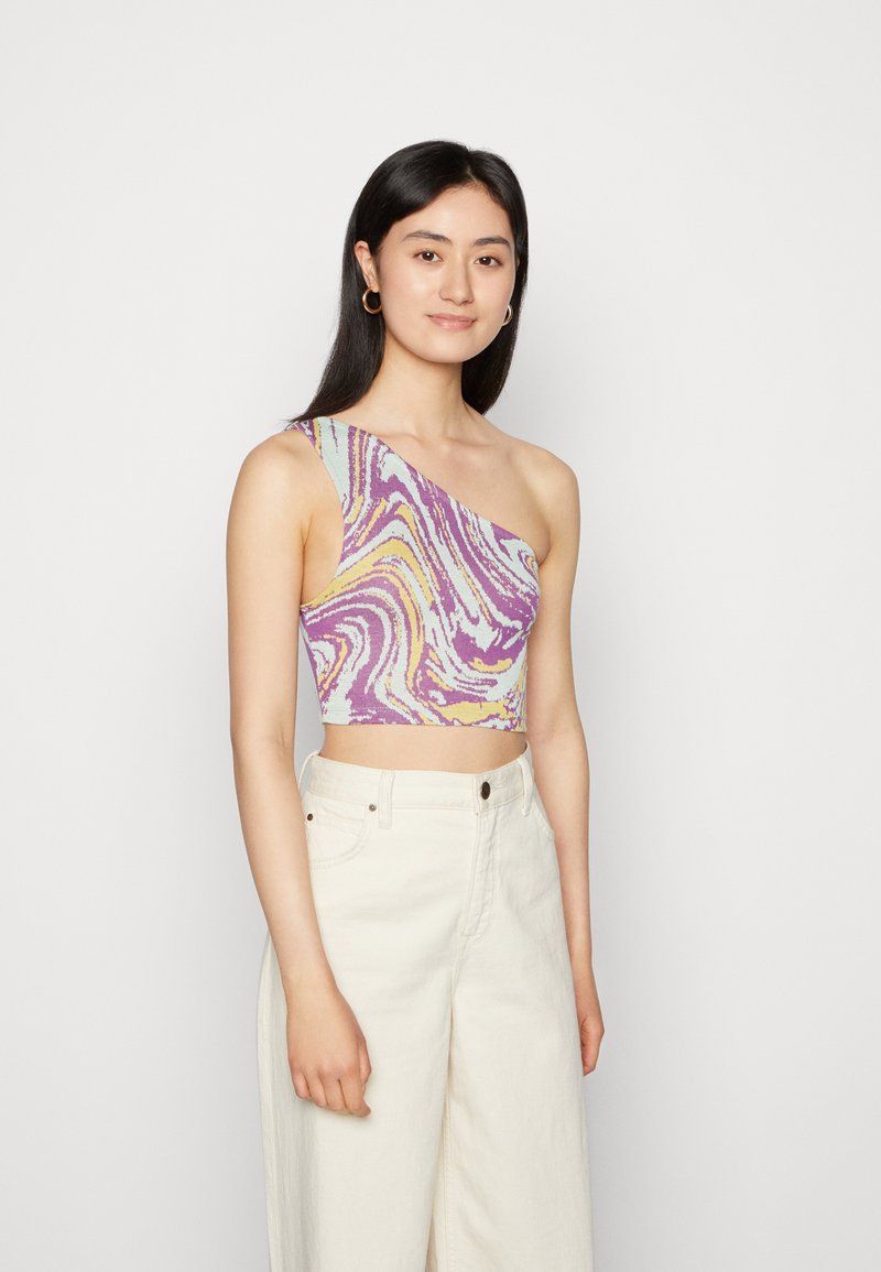 Top cropped de um ombro só com um padrão de espirais coloridas em roxo, amarelo e azul claro, feito de material texturizado; combinado com calças largas em bege.