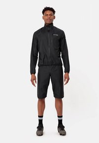 Casaco impermeável preto com fecho éclair, punhos elásticos e calções combinando. O material é leve e de textura suave, adequado para atividades ao ar livre.