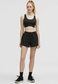 Black athletic set featuring a fitted sports bra with wide straps and loose shorts with an elastic waistband and drawstring.