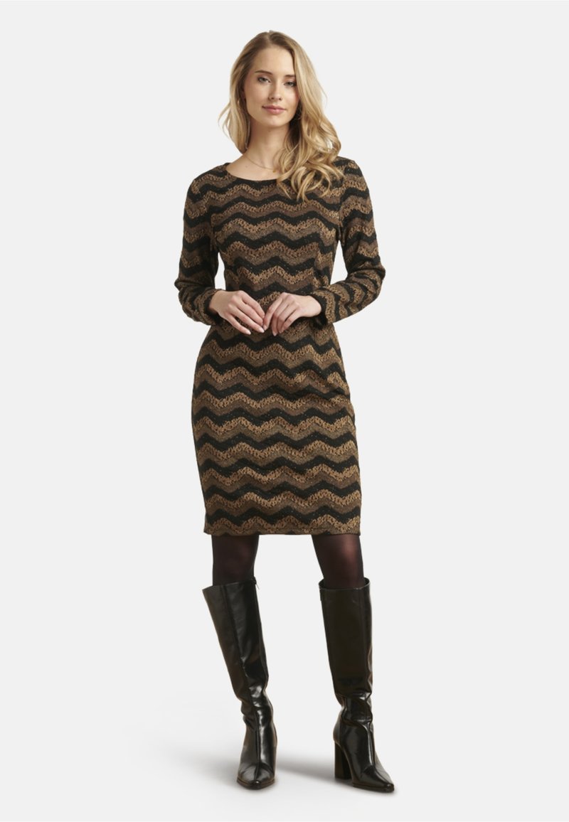 Abito a maniche lunghe con motivo a zigzag in nero, oro e marrone. Realizzato in tessuto texturizzato, ha lunghezza al ginocchio e viene abbinato a stivali neri alti.