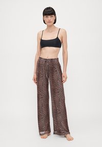 Leopard print, lightweight pants with an elastic waistband and drawstring. Wide-leg design, beige and brown with a sheer texture.