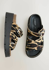 Platform sandale s gornjim dijelom od leopard uzorka od umjetnog krzna, crna gumena potplat, dva preklopna remena i detalj od srebrne kopče.