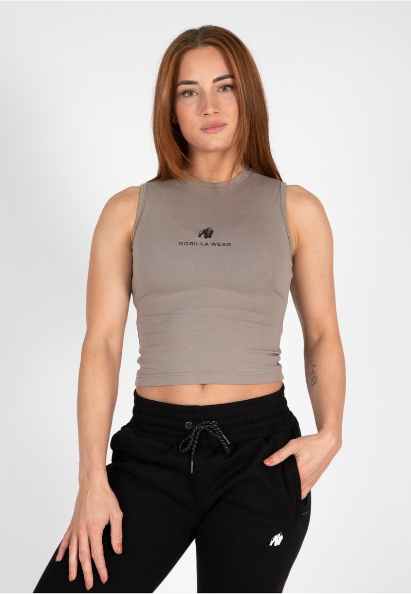 Grijze mouwloze crop top met een aangesloten ontwerp, voorzien van een zwart "GORILLA WEAR" logo. Gecombineerd met zwarte joggerbroeken met zakken.
