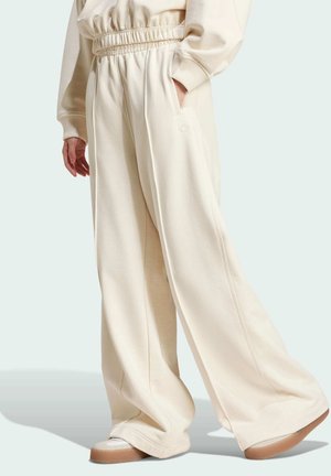 Pantaloni felpati a gamba larga color crema con vita elastica, tasche laterali e un sottile dettaglio del logo. Texture morbida e vestibilità rilassata.