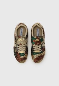 Sneakers met een camouflagepatroon dat is versierd met gouden, groene en bruine pailletten. Beige veters en een tan interieur met branding op de tong.